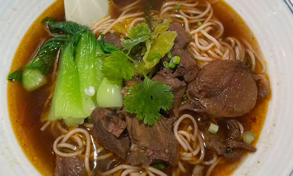 Spicy beef noodles with greens in savory broth at Licious Noodles & Bao, a Chinese Dumpling Restaurant in Rockledge